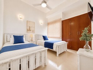 A bedroom with two beds, a wooden wardrobe, a bedside table, a lamp, and a wall-mounted TV. - Charming • Lovely view • Beach • Pool 901 (Cartagena)