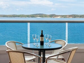 A table with a bottle of wine and glasses on a balcony overlooking a body of water. - Charming • Lovely view • Beach • Pool 901 (Cartagena)
