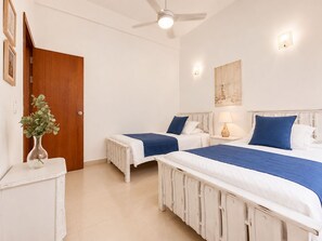 A hotel room with two beds, a wooden door, a white dresser, and a ceiling fan. - Charming • Lovely view • Beach • Pool 901 (Cartagena)
