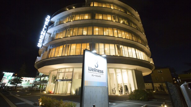 A multi-story building with a sign indicating it is a wellness center. - Three Wellness (Okayama)
