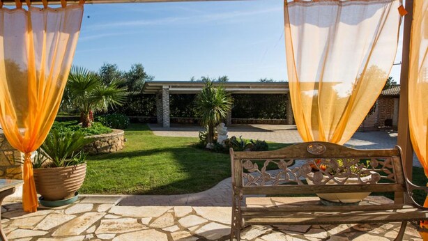 Un patio al aire libre con piso de piedra, un banco de madera y plantas en macetas.