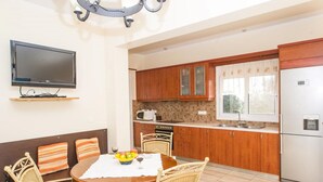 Una cocina compacta con armarios de madera, microondas, refrigerador y un comedor con sillas de mimbre y una mesa.