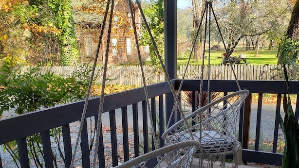 A wooden deck with two white wicker chairs and a table.