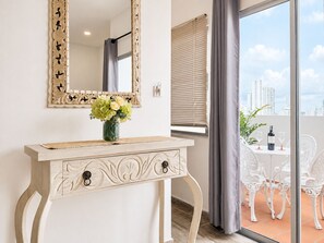 A room with a vanity table, a mirror, a vase with flowers, a window with blinds, and a balcony with outdoor furniture. - Lovely view • Private terrace • Beach • Pool 1404B (Cartagena)