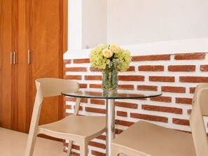 A room with a glass table, two chairs, a vase with flowers, and a brick wall. - Lovely view • Private terrace • Beach • Pool 1404B (Cartagena)