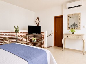 A bedroom with a bed, a TV on a brick wall, a wooden door, a console table, and a mirror. - Lovely view • Private terrace • Beach • Pool 1404B (Cartagena)