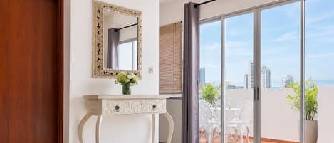 Un dormitorio con un gran ventanal corredera que da a un balcón con mobiliario exterior.