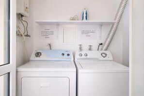 A laundry area with two washing machines, a vent, and safety instructions on the wall. - Charming • Lovely view • Beach • Pool 403 (Cartagena)