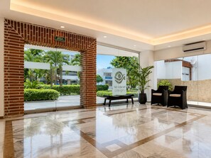Un hall d’hôtel comprenant un comptoir d’accueil, un espace salon et une grande baie vitrée donnant sur l’extérieur.