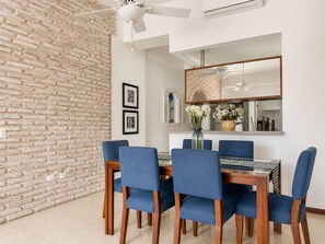 A dining area with a brick wall, a ceiling fan, a dining table with chairs, and a mirror above the table. - Charming • Lovely view • Beach • Pool 403 (Cartagena)