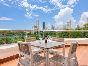 A terrace with a table set for two, overlooking a city skyline and a body of water. - Charming • Lovely view • Beach • Pool 403 (Cartagena)