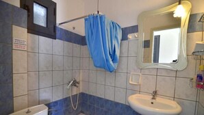 Une salle de bain équipée de toilettes, d’un lavabo, d’une douche et d’un miroir.