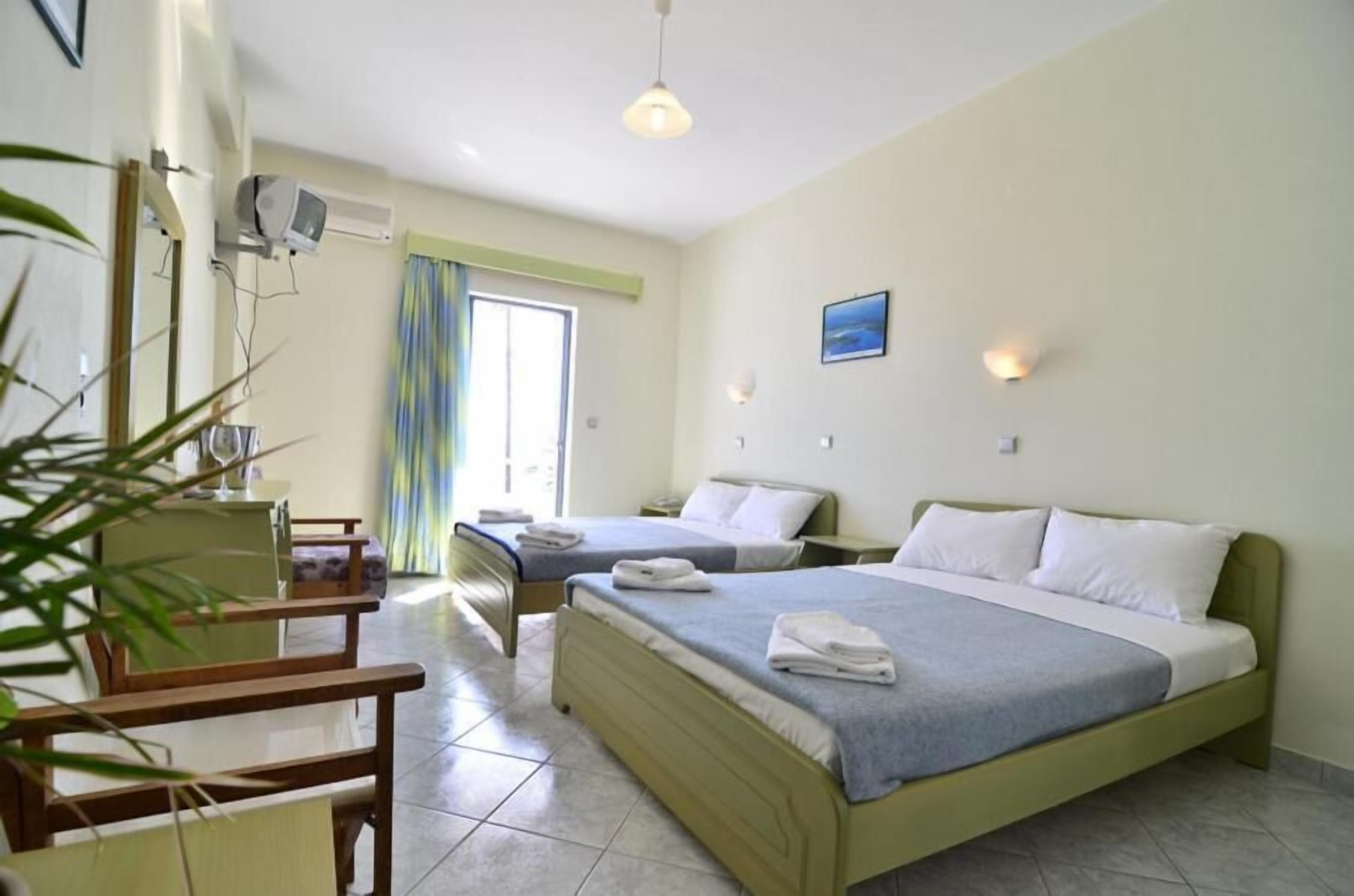 Une chambre d’hôtel avec deux lits, un bureau, une chaise et une fenêtre avec des rideaux.