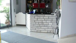 Un espace d’accueil avec un comptoir en briques, une plante en pot et un tableau encadré au mur.