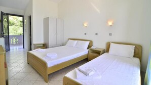 Une chambre d’hôtel avec deux lits, une armoire et une petite table.