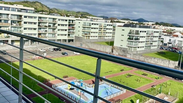 A view from a balcony overlooking a residential area with modern apartment buildings, a playground, and a parking lot. - Azores Paim Apartment T1 (Ponta Delgada)