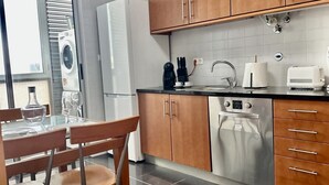 A modern kitchen with wooden cabinets, a built-in oven, and a dishwasher. - Azores Paim Apartment T1 (Ponta Delgada)