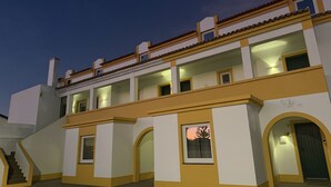 A multi-story building with balconies, arched doorways, and a staircase leading to the entrance.