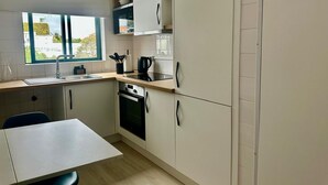 A compact kitchen with a window, a sink, a stove, and a dining area.