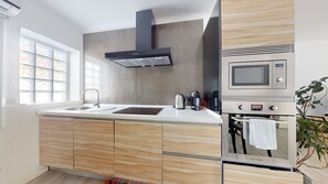 Una cocina moderna con horno empotrado, microondas y hervidor.