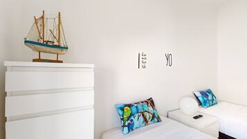 A bedroom with a bed, a nightstand, a dresser, a decorative sailboat, and a wall with the text "kiss miss love like".