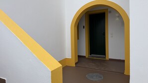 A hallway with a yellow archway leading to a door marked with the letter 'D'.