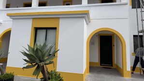 A building with a white and yellow facade, multiple windows, and a balcony.