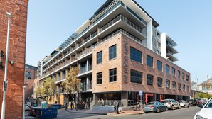A multi-story building with a brick facade, balconies, and a ground-level cafe. - Docklands 409 (Cape Town)