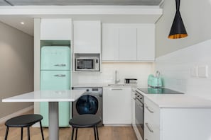 A compact kitchen with a washing machine, microwave, and toaster.