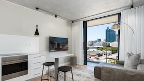 A modern kitchen with a built-in oven and a dining area with a bar stool. - Docklands 409 (Cape Town)