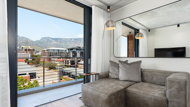 A modern living room with a large window, a grey sofa, and a flat-screen TV. - Docklands 409 (Cape Town)