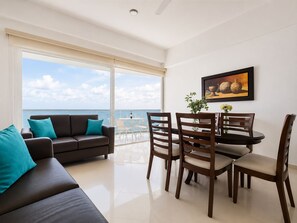 Un soggiorno moderno con un balcone vista mare, una zona pranzo con sedie in legno e un quadro appeso al muro.