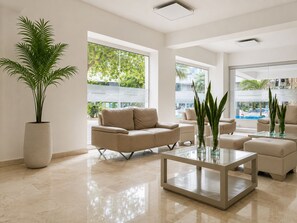 A modern living room with a beige sofa, a glass coffee table, and a potted plant. - Ocean view • Wonderful sunsets • Beach • Pool 1206 (Cartagena)