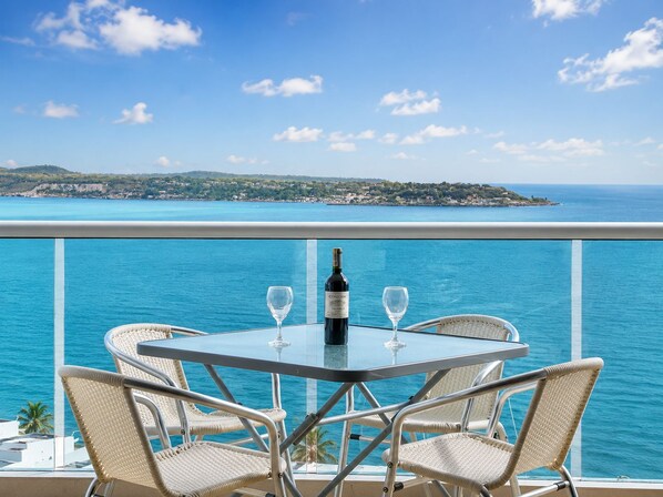 A balcony with a table, two chairs, a bottle of wine, and two wine glasses.