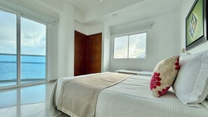 A bedroom with a large bed, a wardrobe, and a window with a view of the sea. - Ocean view • Wonderful sunsets • Beach • Pool 1206 (Cartagena)