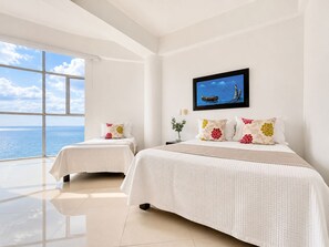 A hotel room with two beds, a large window with a view of the sea, and a painting on the wall. - Ocean view • Wonderful sunsets • Beach • Pool 1206 (Cartagena)
