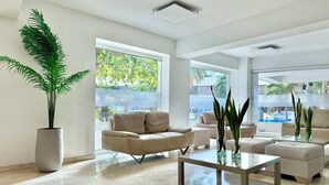A spacious living area with a large potted plant, a glass coffee table, and a beige sofa. - Ocean view • Wonderful sunsets • Beach • Pool 1206 (Cartagena)