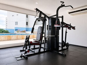 Ein Fitnessraum mit einem Squat-Rack, einer Langhantelbank und Gewichtsplatten.