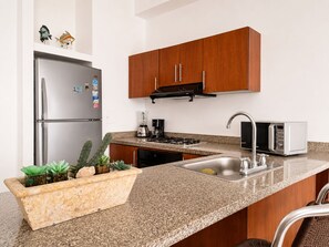 Una cucina moderna con frigorifero in acciaio inossidabile, forno a microonde, lavello e pensili in legno.
