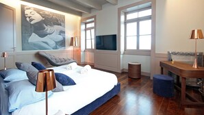 Une chambre avec un grand lit, un téléviseur fixé au mur et une fenêtre donnant sur un beau paysage.