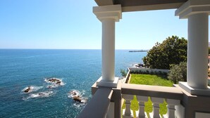 Un balcon avec vue sur la mer et un navire au loin.
