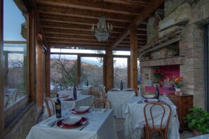 A dining area with tables set for a meal, wooden beams on the ceiling, and a view of the outdoors. - Agriturismo Ardene (Montepulciano)