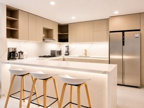 A modern kitchen with a central island, bar stools, a built-in oven, and a stainless steel refrigerator. - Penthouse • Private pool • Ocean view • Beach 1803 (Cartagena)