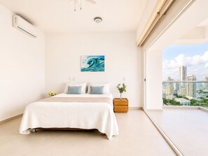Une chambre à coucher comprenant un lit, une table de chevet, une fenêtre donnant sur la ville et un climatiseur fixé au mur.