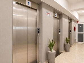 Un couloir avec trois portes d’ascenseur, chacune étant marquée d’un numéro.