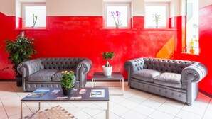 Una sala de estar moderna con dos sofás grises, una mesa de centro con revistas y plantas en macetas.