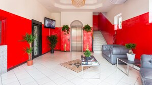 Un vestíbulo con decoración roja y blanca, una escalera, un sofá y plantas en macetas.