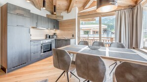 A modern kitchen with grey cabinets and a dining area with a table and chairs. - AlpenParks Chalet & Apartment Alpina Seefeld (Seefeld in Tirol)