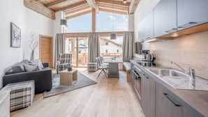 A modern kitchen with a wooden ceiling, a dining area with a table and chairs, and a living room with a sofa and ottoman. - AlpenParks Chalet & Apartment Alpina Seefeld (Seefeld in Tirol)
