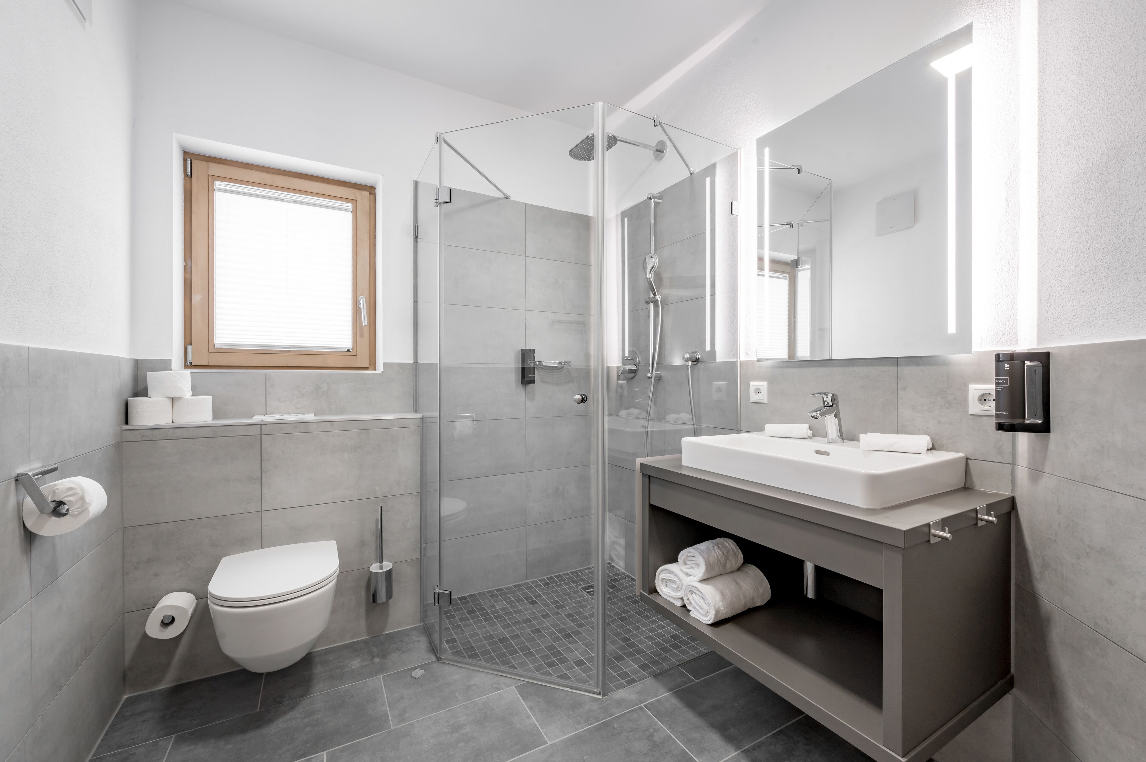 Une salle de bain moderne avec une douche à parois de verre, un lavabo blanc et des toilettes.